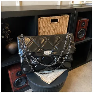 Close-up of quilted black leather shoulder bag with a sparkling diamond-studded square buckle