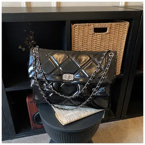 Close-up of quilted black leather chain bag with rhinestone lock in a home setting