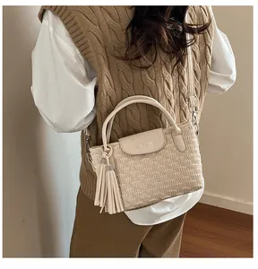 Detail of cream bucket bag with wave ripple texture, fringe tassel and UINUIN embossed logo