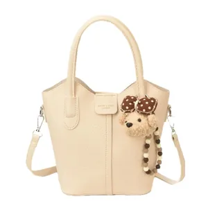 Cream soft leather bucket bag with top handle and cute teddy bear charm pendant