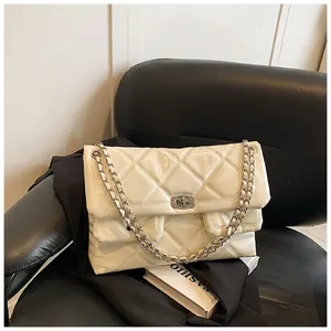 Detail view of cream quilted leather bag with silver diamond-studded turn-lock closure