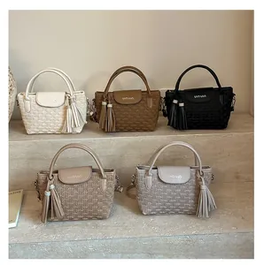 Collection of textured bucket bags in neutral tones with tassels and dual handles