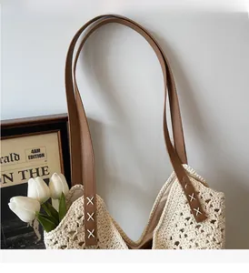 Detail of crochet tote bag with brown leather strap and intricate stitching on cream cotton