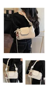 Detail of cream fabric crossbody bag with braided handle and brown bear charm accessory