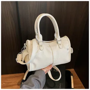 Detail of white lychee pattern leather boston bag featuring silver metal rivets and handles