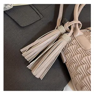 Close-up of beige bucket bag featuring elegant long tassels with sparkling rhinestone details