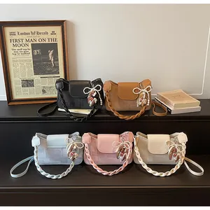 Close-up of stylish rectangular crossbody bags in five colors with woven handles and charms
