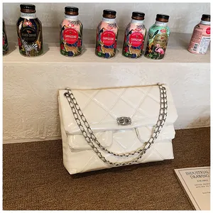 Detail of quilted cream leather chain bag with metallic twist lock on woven table