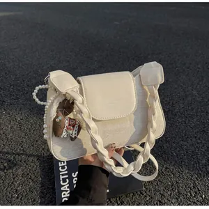 Detail of cream white crossbody bag featuring pearl chain and woven strap texture