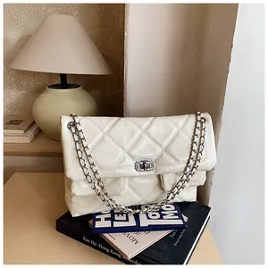 Close-up of white quilted leather texture with silver metal turn-lock on the shoulder bag