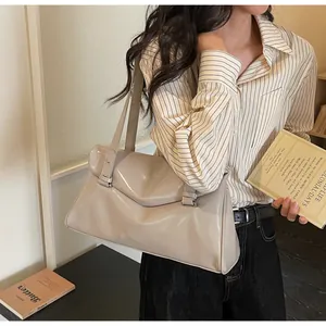 Detail of light grey shoulder bag with flap closure and buckle straps in a lifestyle shot