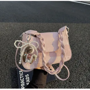 Detail of pink vintage square bag with braided handle, horse charm and pearl bow accessory