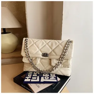 Close-up of quilted cream shoulder bag with glossy finish and silver chain strap details