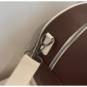 Detalle de bolsa de viaje de cuero marrón con cremallera metálica y correa de lona