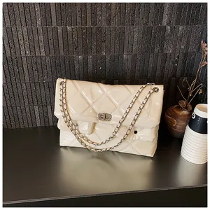 Close-up of beige quilted patent leather crossbody bag with silver chain and metal lock