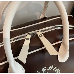 Detalle de bolsa de viaje estilo béisbol vintage con cremallera doble y asa de cuero PU