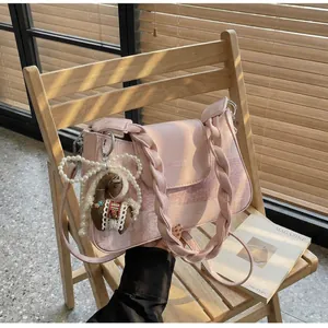 Detail of pink plaid handbag with pearl bow, pony charm and woven handle on a chair
