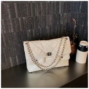 Detail of white quilted chain bag with high-gloss finish and silver metal turn-lock closure