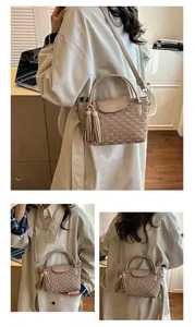 Detail view of beige water ripple bucket bag with tassel charms and metallic logo