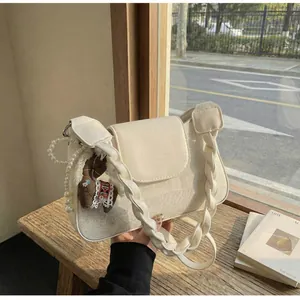 Detail of cream canvas handbag with woven handle, pearl chain and brown pony charm
