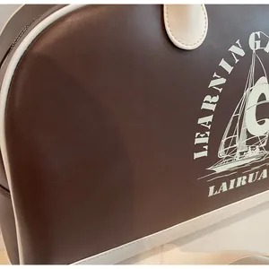 Detalle de bolso vintage de cuero marrón con borde blanco y diseño de velero