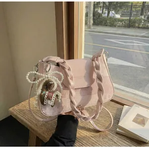 Detail of pink vintage crossbody bag with woven handle, pearl chain and horse charm