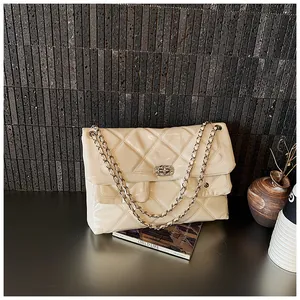 Detail of cream quilted patent leather bag with gold chain strap and metal turn-lock