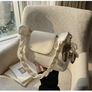 Detail of cream vintage underarm bag with woven handle and brown horse pearl pendant