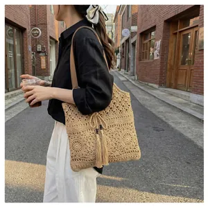 Detail of hand-woven crochet tote bag with fringe tassels and vintage leather straps