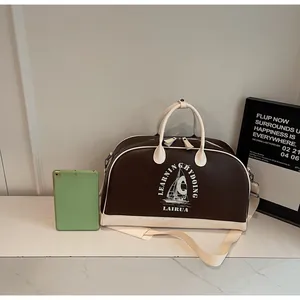 Detalle del bolso de béisbol vintage con ribetes en contraste y estampado náutico sobre mármol