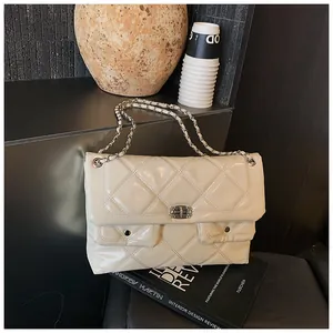 Detail of cream quilted patent leather bag with silver chain and dual pockets