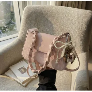 Close-up of pink leather crossbody bag with braided handle and pearl charm detail