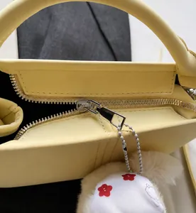 Detail of smooth silver zipper on a light yellow soft leather handbag with neat stitching