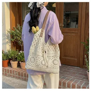 Detail of bohemian hollow crochet tote bag with leather strap and tassel accents