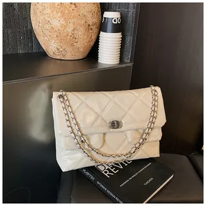Close-up of cream quilted patent leather shoulder bag with silver chain and metal buckle