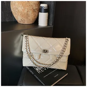 Detail shot of a cream quilted leather crossbody bag with silver chain straps and flap closure