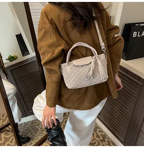 Close-up of beige woven bucket bag featuring elegant tassels and wave pattern detail