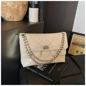 Detail of quilted glossy leather bag featuring crystal buckle and metal chain strap