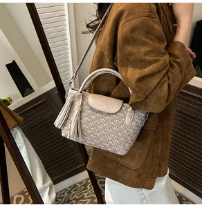 Close-up of beige water-ripple bucket bag with double tassels and UIAUIA logo detail