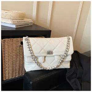 Close-up of quilted white crossbody bag with rhinestone buckle and silver chain