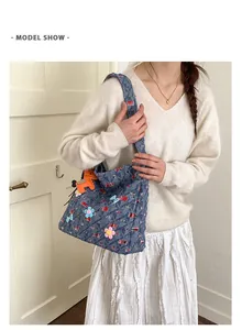 Detail der blauen Denim-Tragetasche mit 3D-Blumen und orangefarbenem Pferdeanhänger