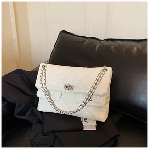 Close-up of cream quilted patent leather bag with silver chain and crystal lock
