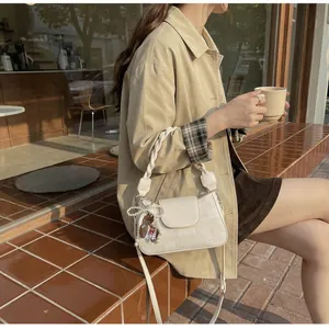 Detail of cream vintage square bag with woven handle and small horse charm on a model