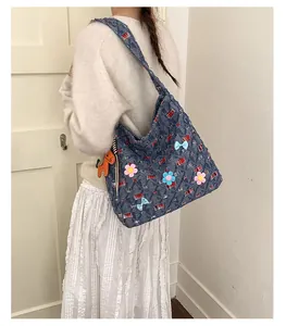 Detail der blauen Denim-Tragetasche mit bunten 3D-Blumenapplikationen und Hundeanhänger