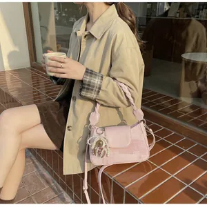 Detail of pink canvas crossbody bag with woven handle and cute bear charm pendant