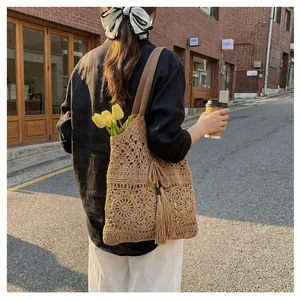 Detail of hand-woven hollow knit pattern and long tassels on a large khaki tote bag