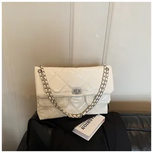 Detail of quilted glossy patent leather bag with silver chain strap and twist lock