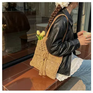 Detail of hollow floral crochet tote bag with tassel pendant and leather straps