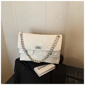Detail of cream quilted crossbody bag featuring glossy patent leather and silver chain strap