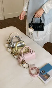 Close-up of minimalist cylindrical Boston bags in five colors with plush charms and straps